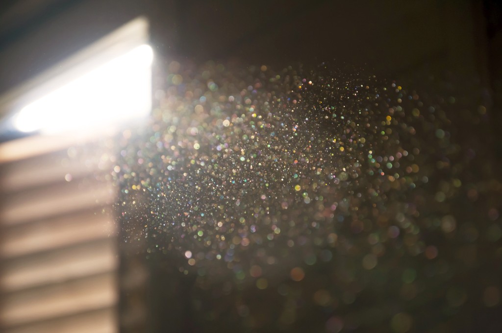 Sunlight through blinds illuminating dust particles floating in an indoor room