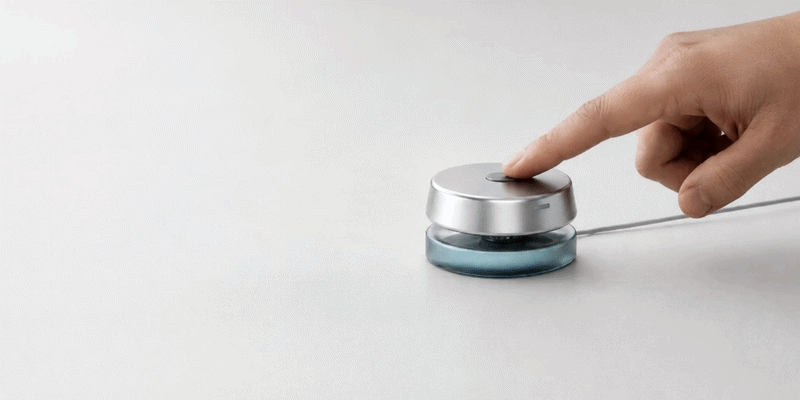 A finger pressing the top of the Ayasense hub; the base lights up in response